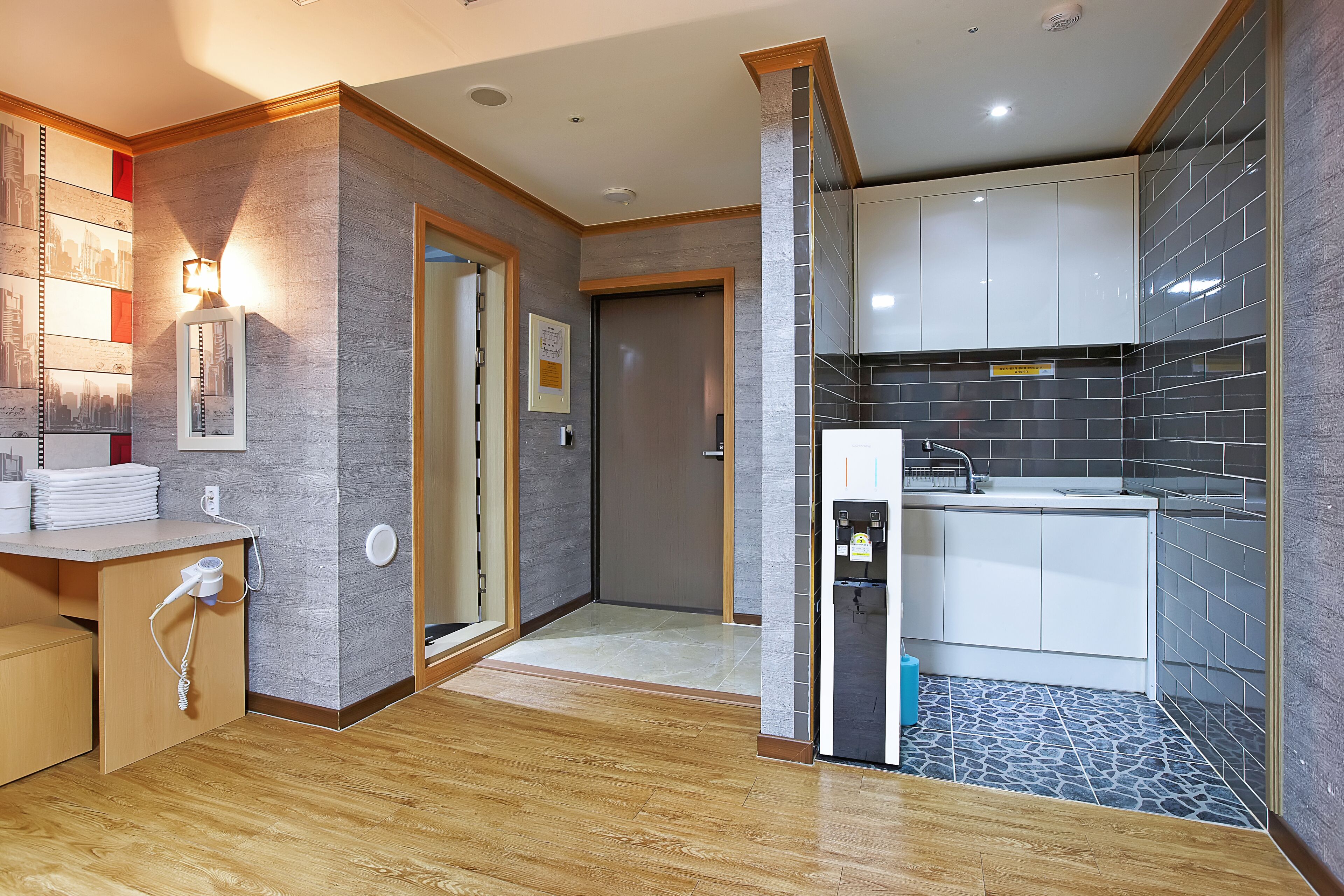 Une cuisine moderne avec un dosseret de carrelage gris, un plancher en bois et des armoires blanches.
