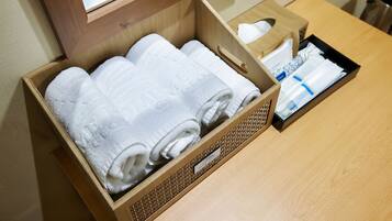 A wooden box containing neatly folded white towels and a tissue box on a wooden table.