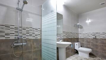 Een moderne badkamer met een douchecabine van glas, een wastafel op een voetstuk en een toilet.