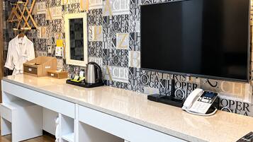 Una recepción de hotel con un televisor de pantalla plana grande, un teléfono y una cafetera.