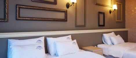 A hotel room with two beds, each with white bedding and pillows, a headboard, and wall-mounted lamps.