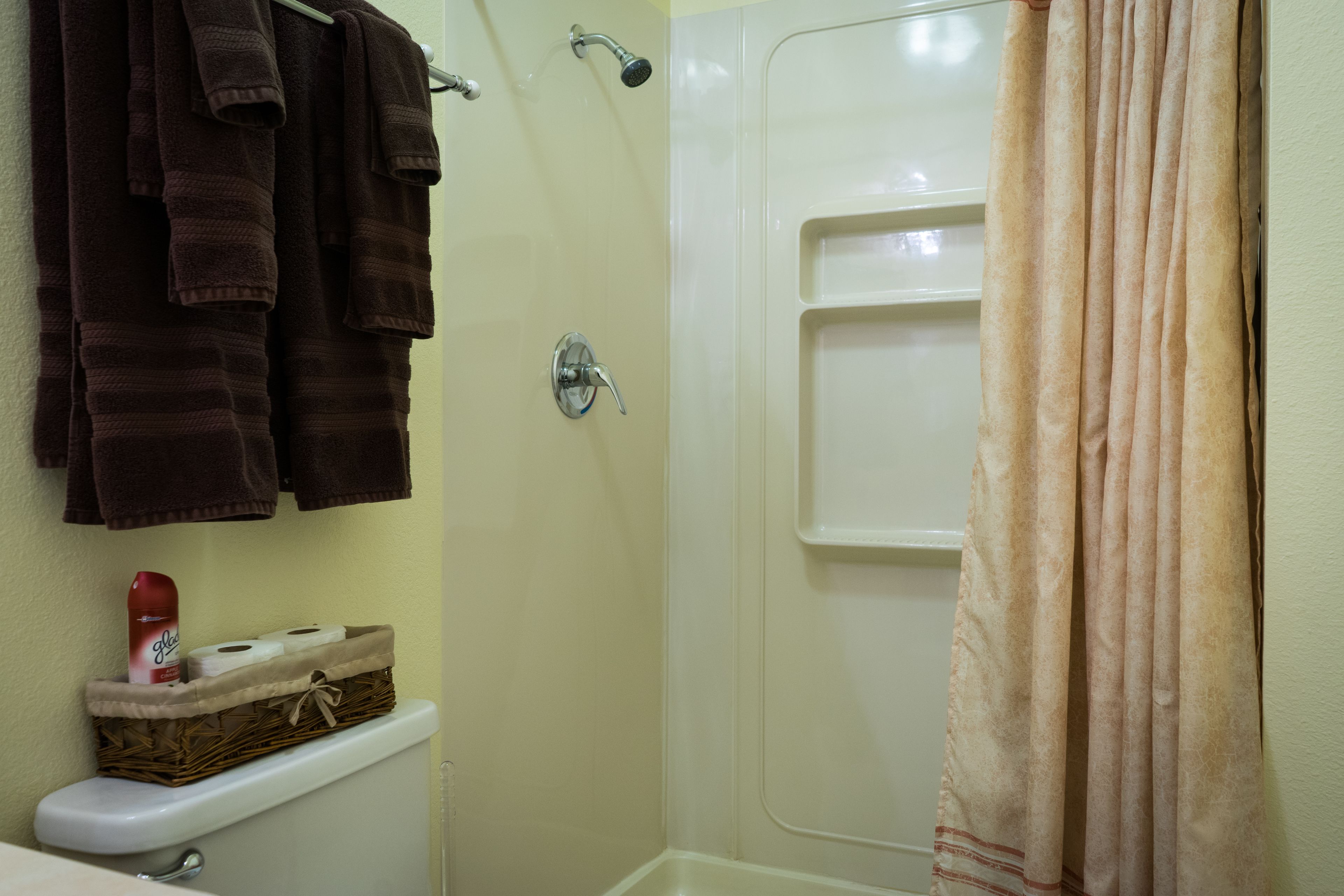 Un baño con inodoro, ducha y toallero con toallas.
