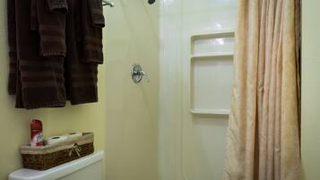 Un baño con inodoro, ducha y toallero con toallas.