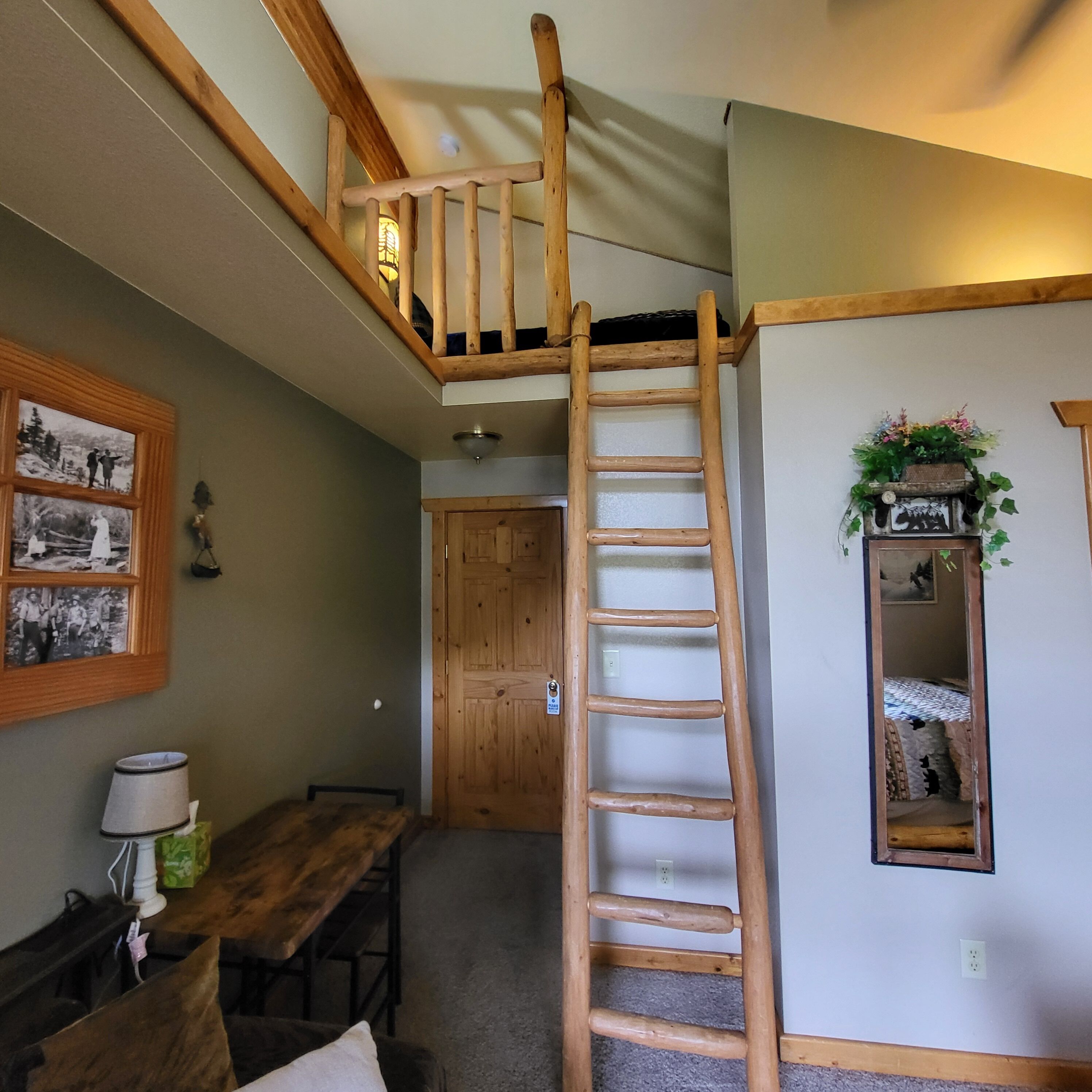 A wooden loft bedroom with a wooden ladder leading to a lofted sleeping area.