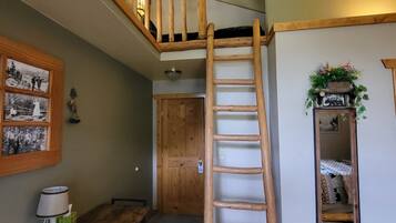 Un dormitorio estilo loft con escalera de madera que lleva a una zona de descanso elevada.