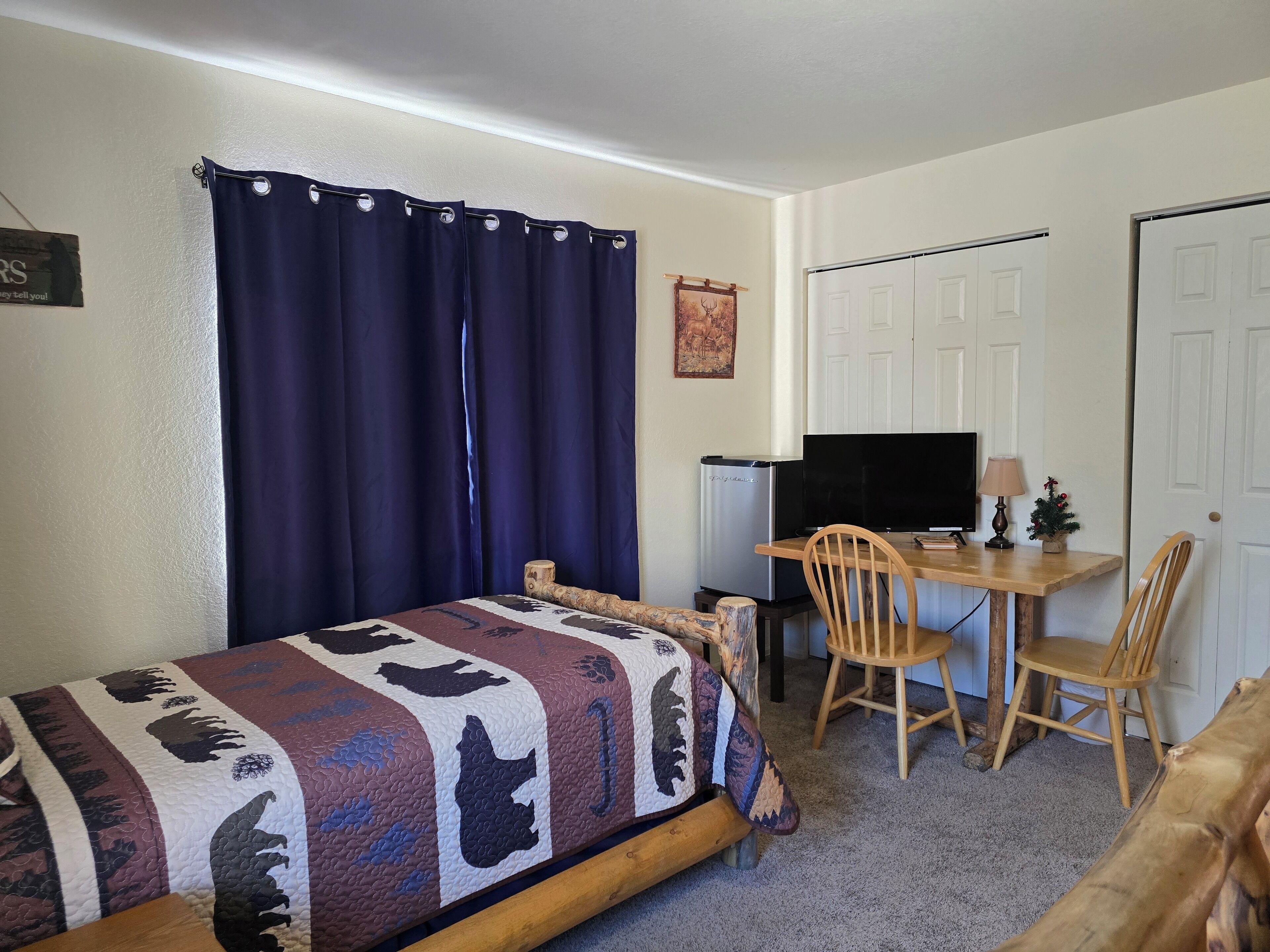 A small, cozy room with a bed, a desk, a television, and a chair.