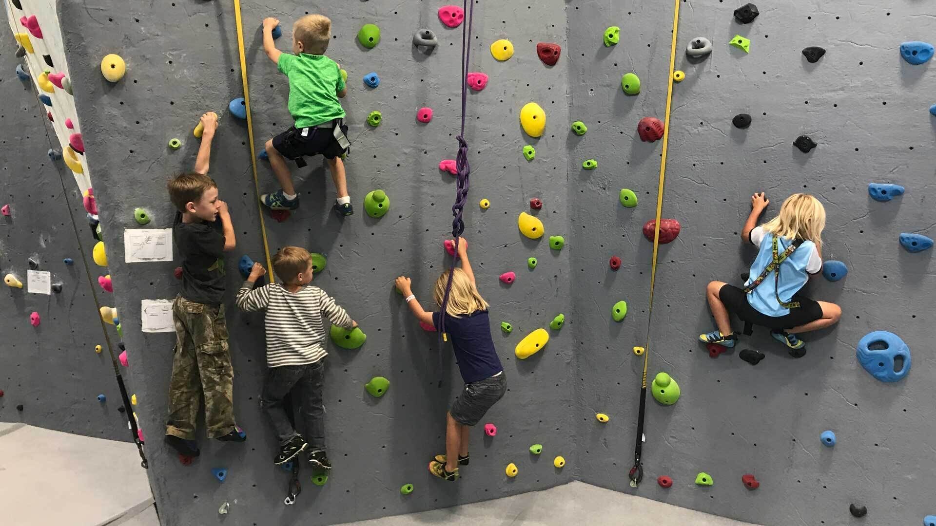 A climbing wall with various colored holds and a rope for safety.