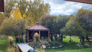 A gazebo in a garden with a wooden deck and outdoor seating. - Buffalo Peaks B&B (Buena Vista)