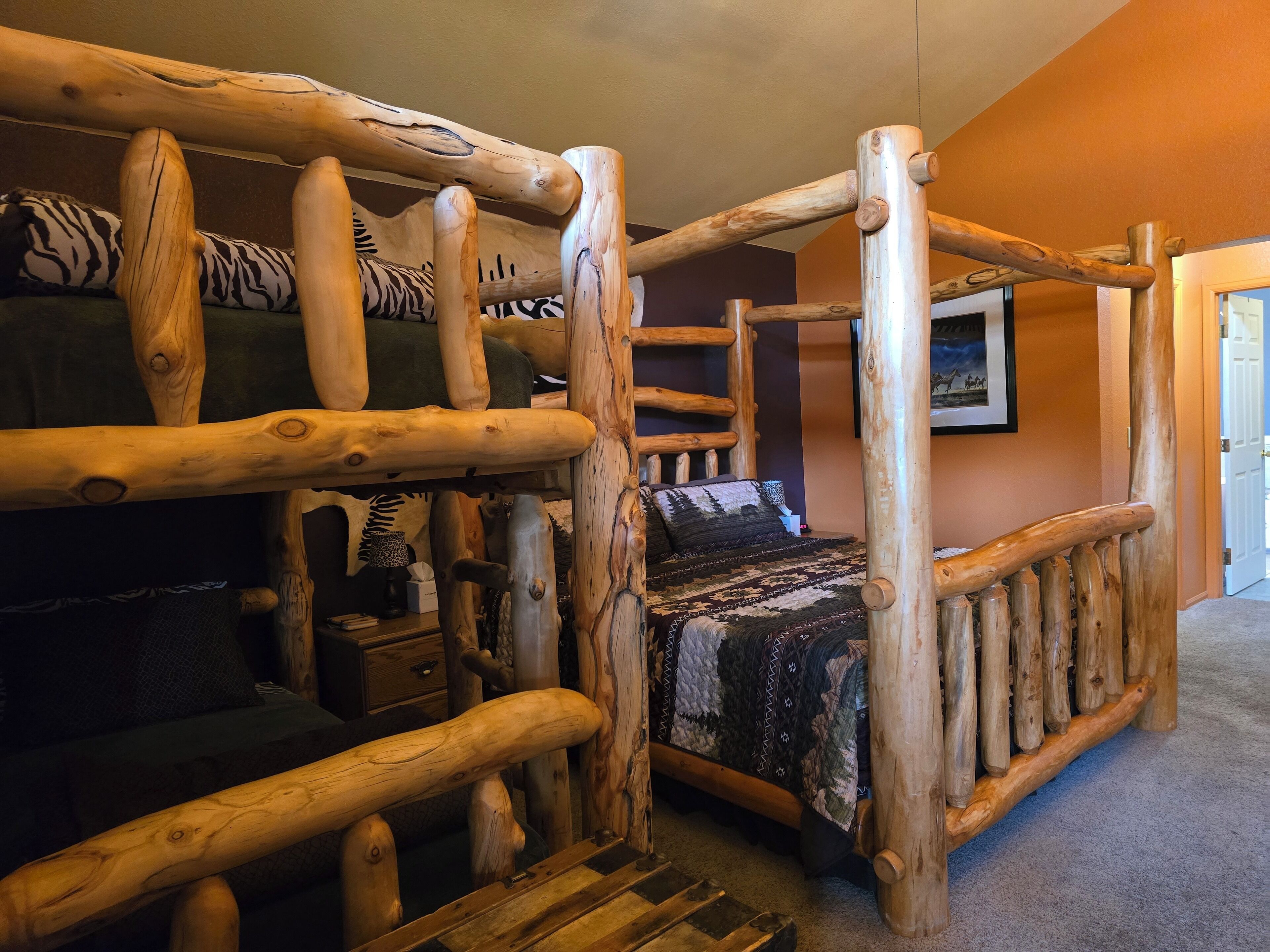 A rustic wooden bunk bed with a ladder, a small bedside table, and a patterned bedspread.