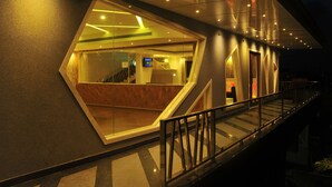 Une entrée d’hôtel moderne avec une façade en verre, un escalier menant à l’intérieur et une enseigne indiquant la présence d’un restaurant.