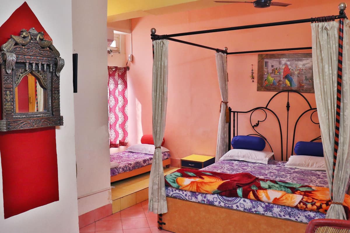 A room with a four-poster bed, a small table, and a mirror with an ornate frame.