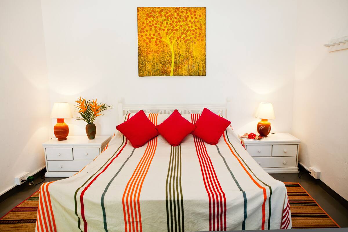A hotel room with a bed, two nightstands, two lamps, and a painting on the wall.