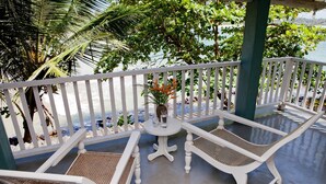 A white outdoor seating area with two chairs and a small table, surrounded by a white railing, overlooking a beach. - Talalla Bay Beach House (Talalla)