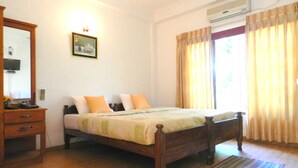 A bedroom with a wooden bed, a bedside table, a mirror, and a wall-mounted air conditioner. - Paradise Inn (Kandy)