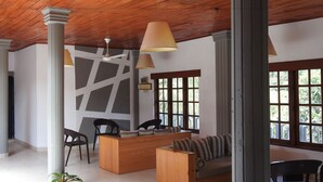 A spacious lobby with a wooden ceiling, a reception desk, seating area, and large windows. - Paradise Inn (Kandy)