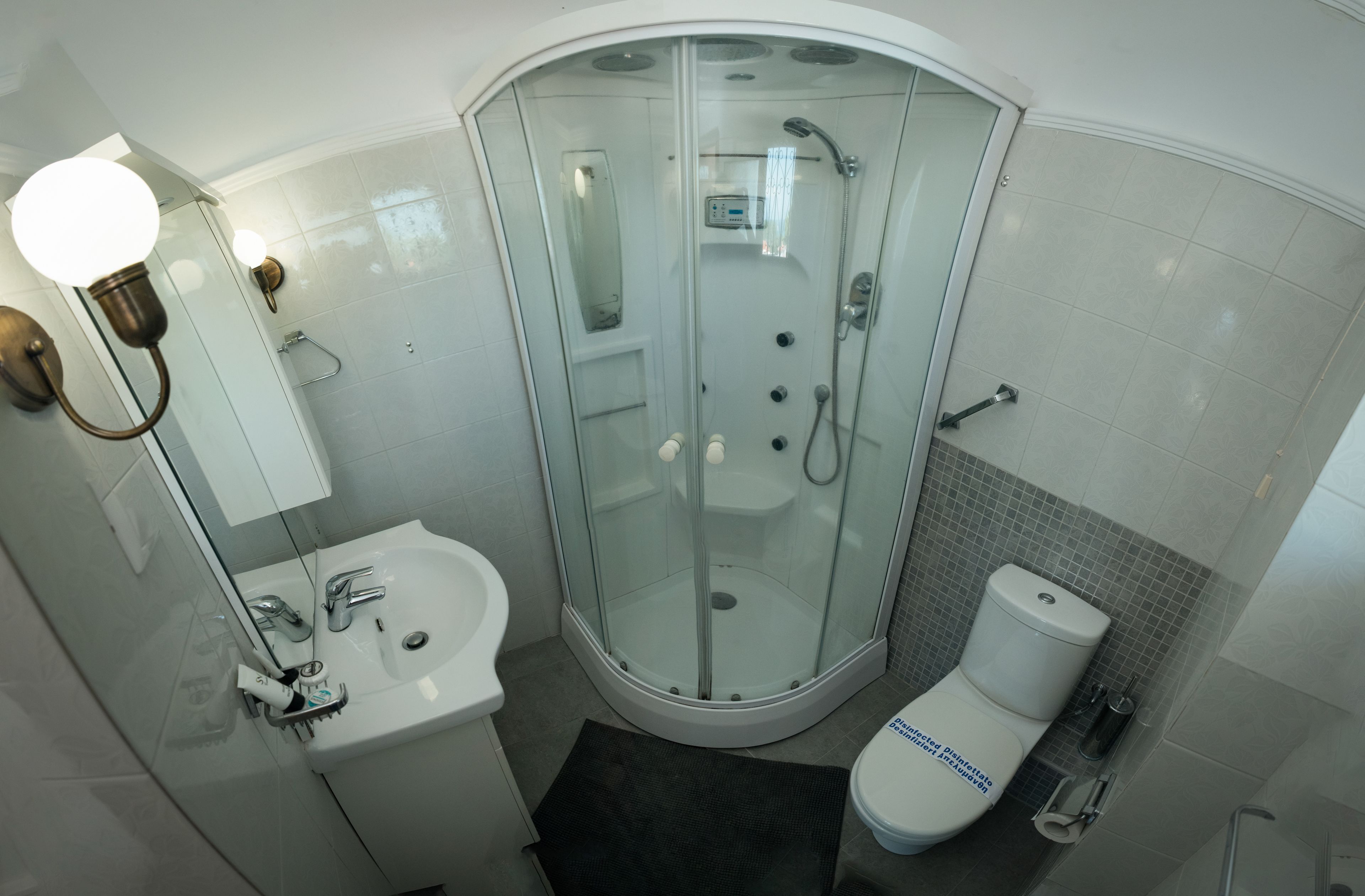 Un baño moderno con ducha envuelta en vidrio, un lavamanos blanco y un inodoro.