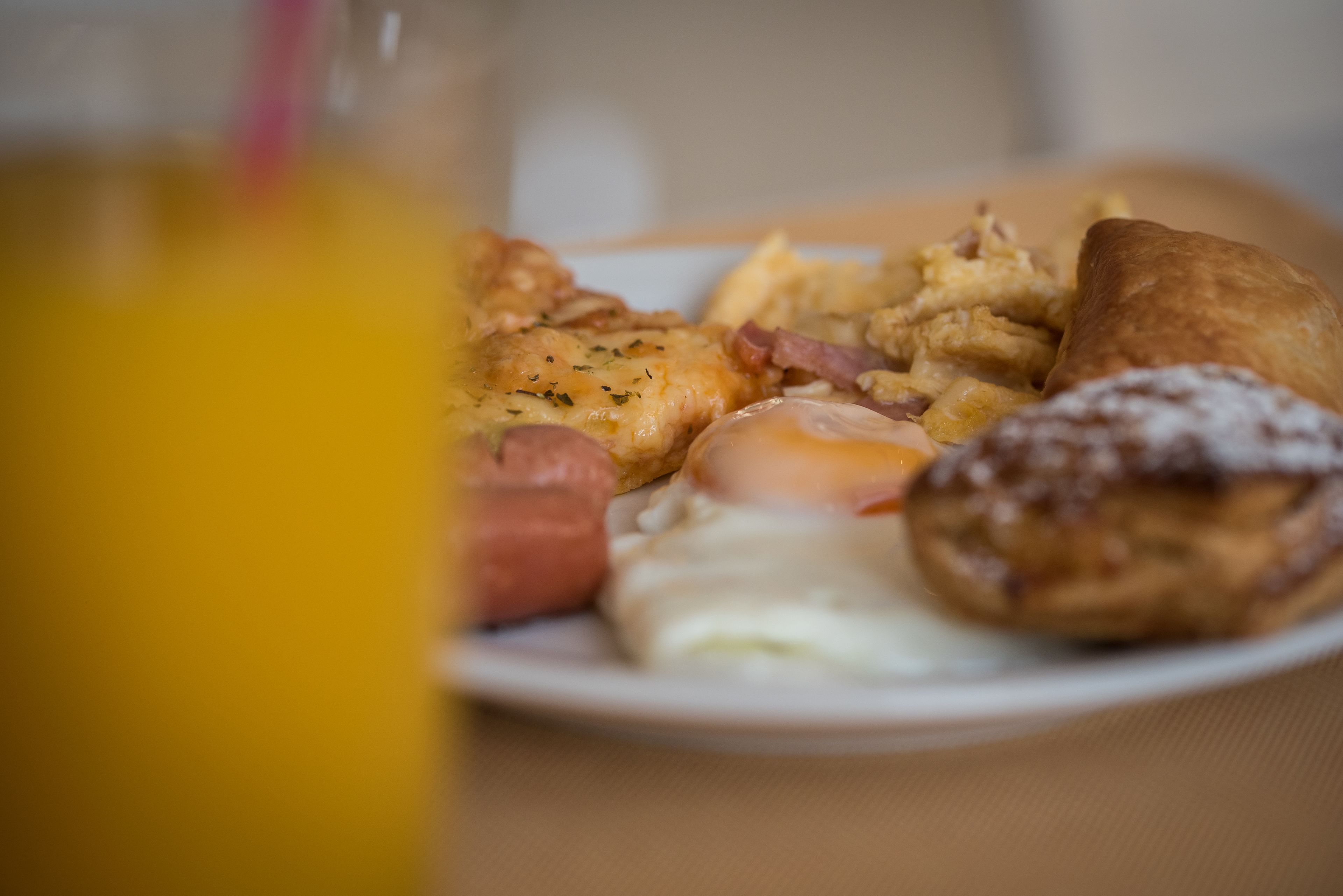 A breakfast plate with eggs, bacon, sausage, and pastries.