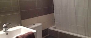 Un baño con un lavabo blanco, un espejo y una zona de ducha con cortina blanca.
