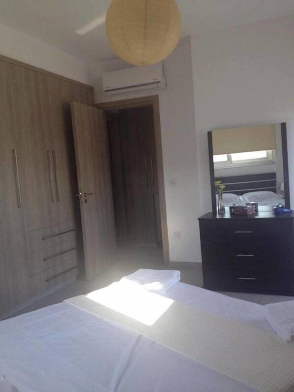 Un dormitorio con una cama, un armario, una cómoda y un espejo.