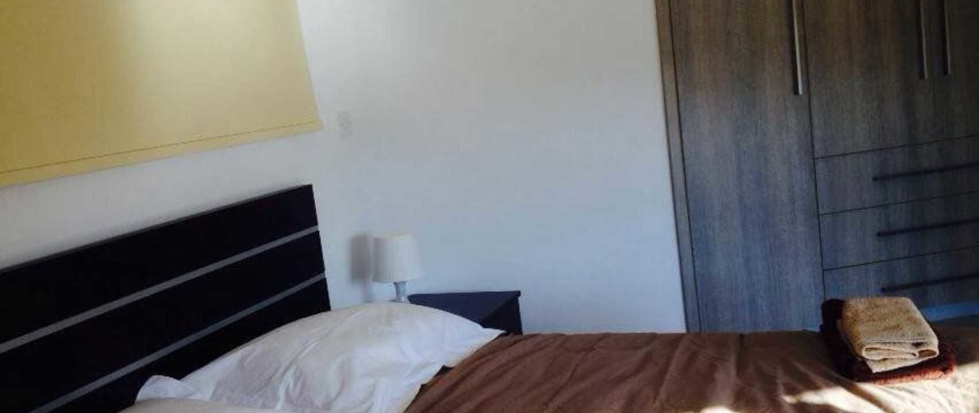 A bedroom with a bed, a nightstand, a lamp, and a wardrobe.
