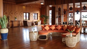 Um hall amplo com um sofá de canto espaçoso, móveis de vime e plantas decorativas.