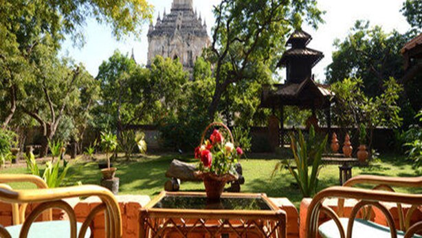 A courtyard with a temple in the background, surrounded by trees and a small pagoda. - KMA Bagan Hotel River View (Nyaung-U)
