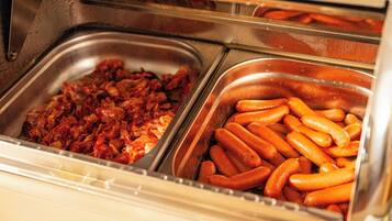 A buffet with two trays of food, one with what appears to be bacon and the other with sausages.
