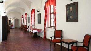 A dining hall with red curtains, wooden chairs, and a table with a white tablecloth. - Hotel Adalbert (Prague)