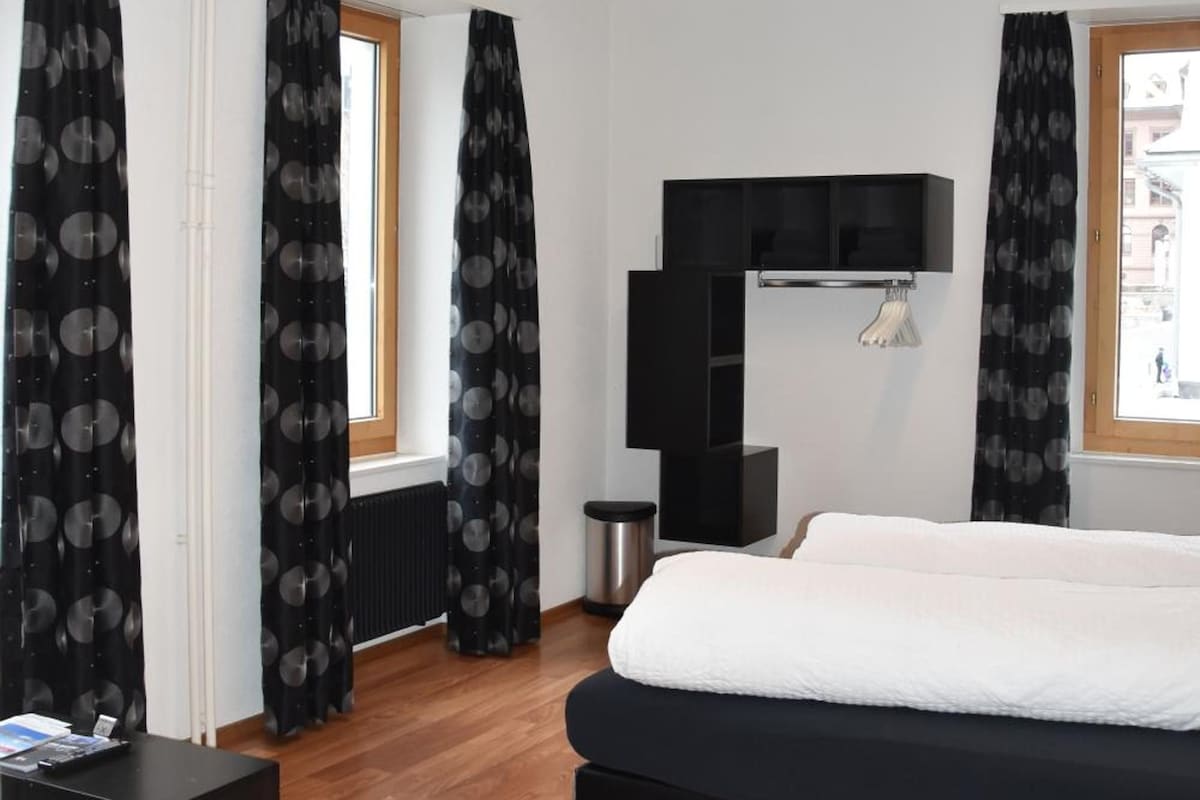 Una habitación de hotel moderna con una cama grande, un escritorio y un armario.