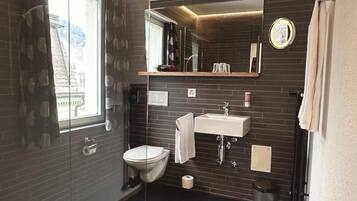 Un bagno moderno con pareti divisorie in vetro, un water, un lavandino e uno specchio.