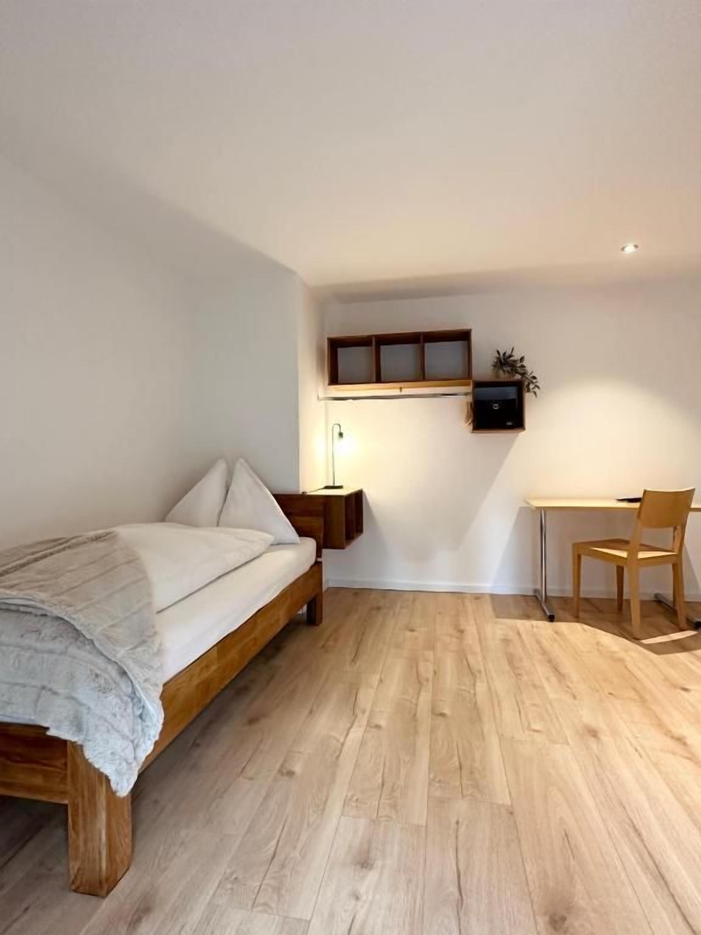 Une chambre à coucher avec un lit en bois, un bureau et une chaise.