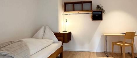 A bedroom with a wooden bed, a desk, and a chair.
