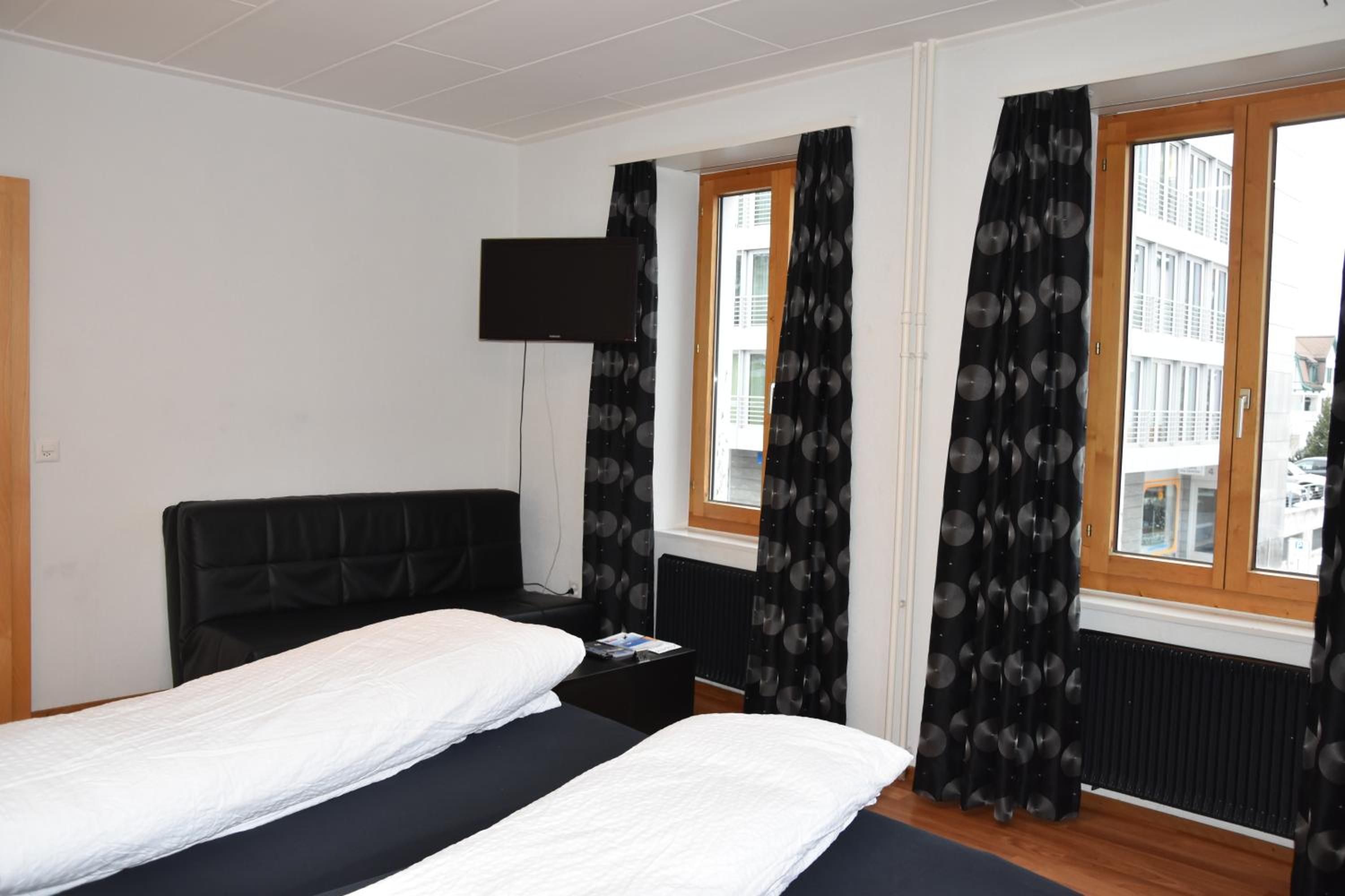 Een hotelkamer met een bed, een flatscreen televisie aan de muur en een raam met gordijnen.