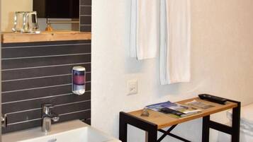 Un baño con lavamanos blanco, repisa de madera y toallero.