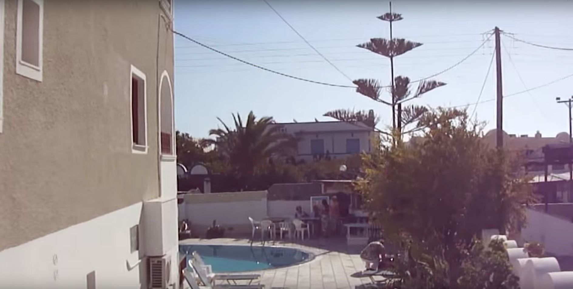 A residential area with a swimming pool, a building with a balcony, and a street lamp.