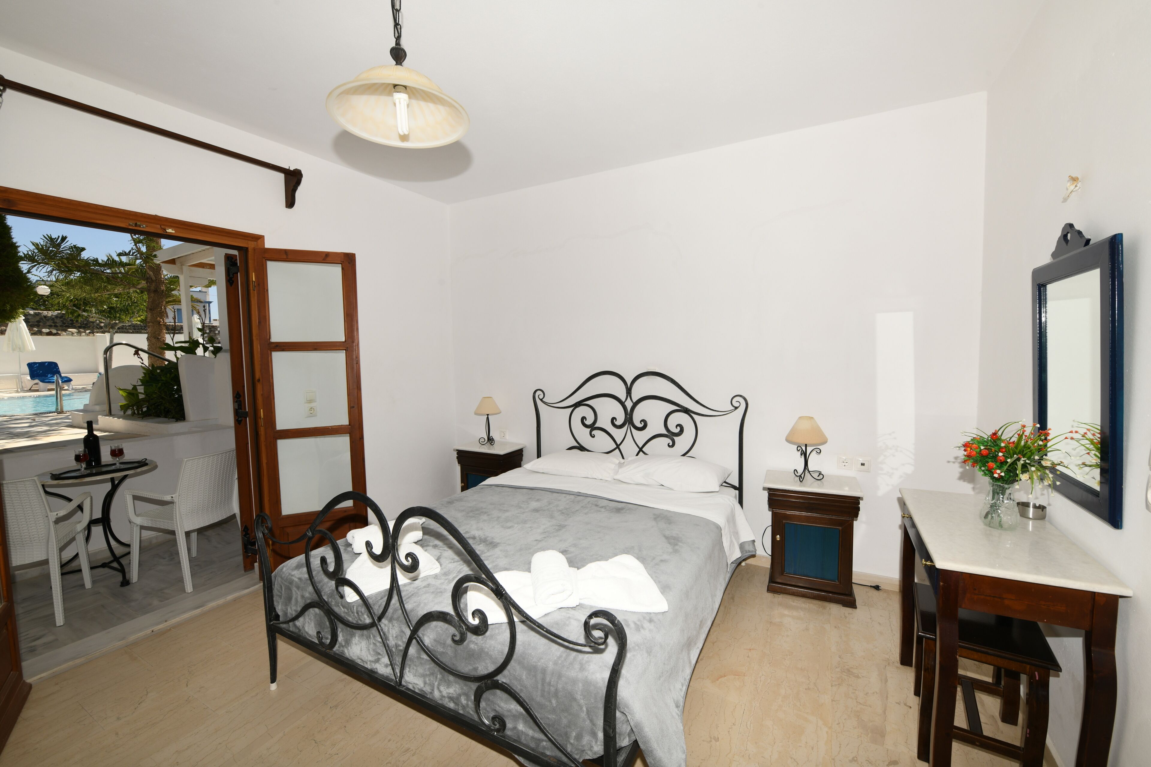 Un dormitorio con cama, mesitas de noche, escritorio y silla.