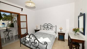 Un dormitorio con cama, mesitas de noche, escritorio y silla.