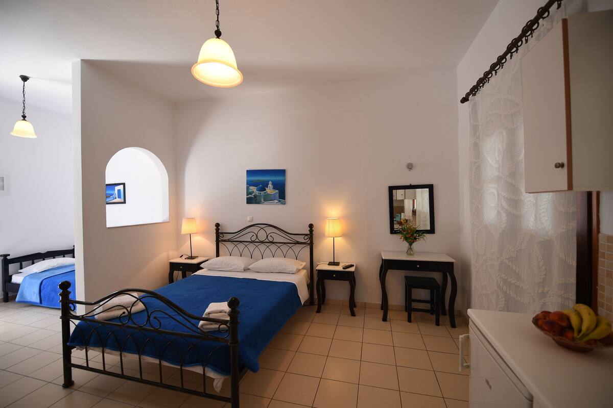 Un dormitorio con cama, mesitas de noche, escritorio y cómoda.