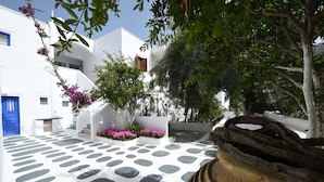 A courtyard with white buildings, a blue door, and a stone pathway. - Sunflower Santorini (Santorini)