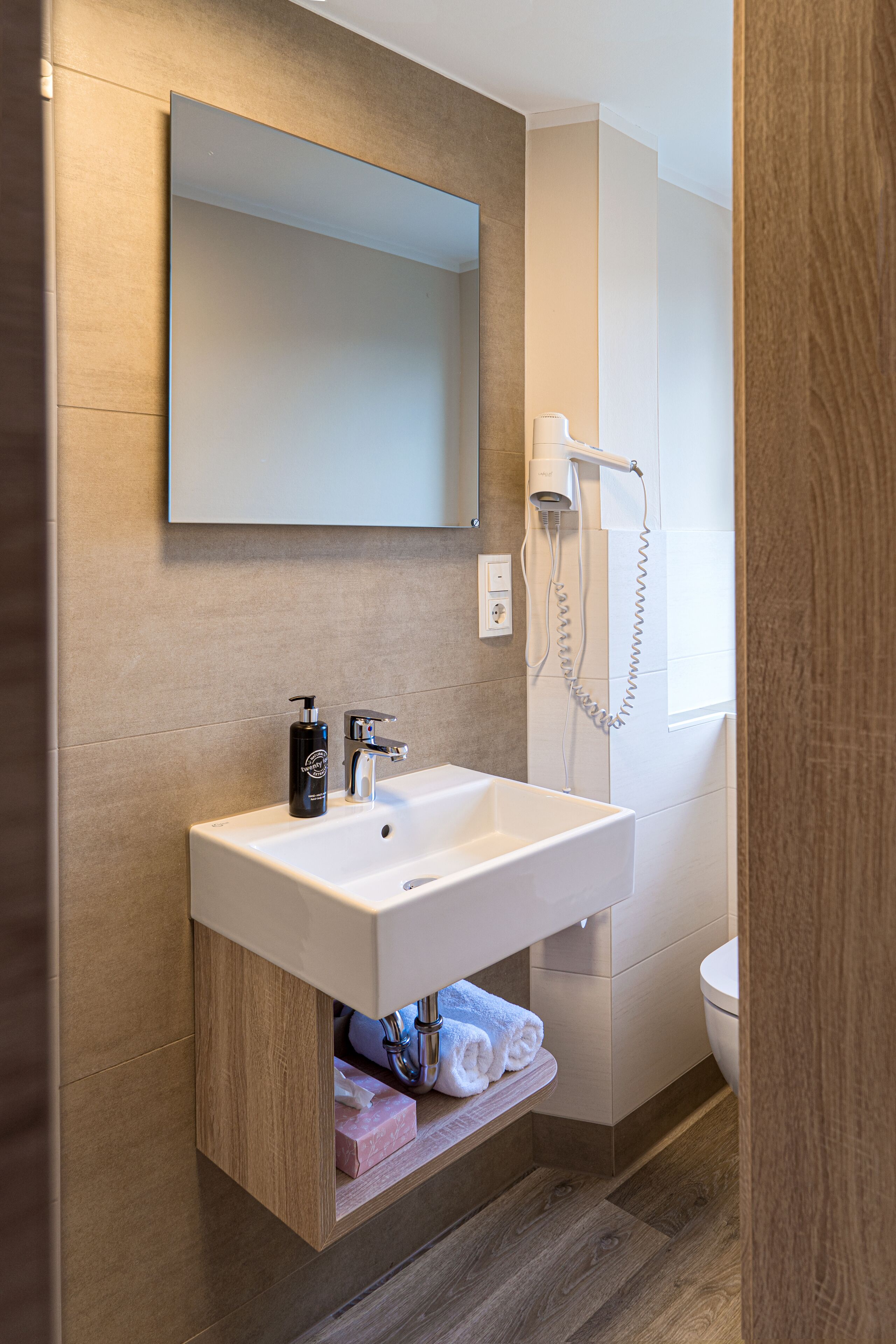 Ein modernes Badezimmer mit Waschbecken, Spiegel und Dusche.