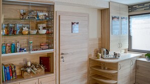 A modern kitchen with wooden cabinetry, a glass display case, and a built-in stove. - Pension Sartor (Altenberg)
