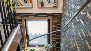 A staircase with a wooden handrail, a potted plant on the left, and framed sports memorabilia on the wall. - Pension Sartor (Altenberg)