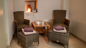 Two wicker armchairs with cushions, a small wooden table with a tray, and a wall-mounted shelf with a lamp and radio. - Pension Sartor (Altenberg)