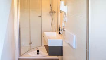 Un baño moderno con ducha de vidrio, lavamanos blanco y un inodoro.