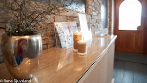 Un área de recepción con pared de piedra, puerta de madera y mostrador de vidrio.