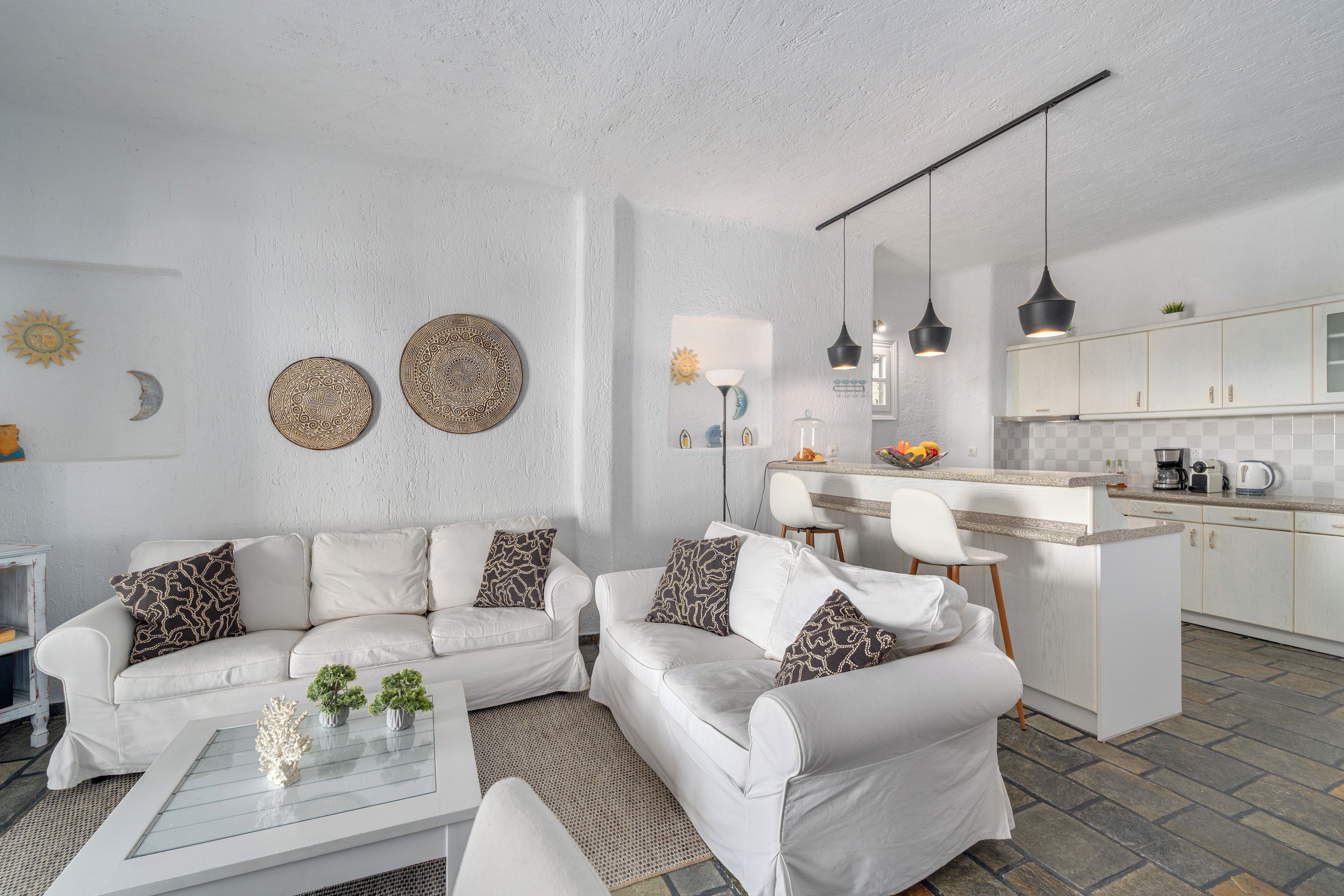 Un salon moderne avec un ensemble de canapés blancs, une table basse et des assiettes décoratives accrochées au mur.