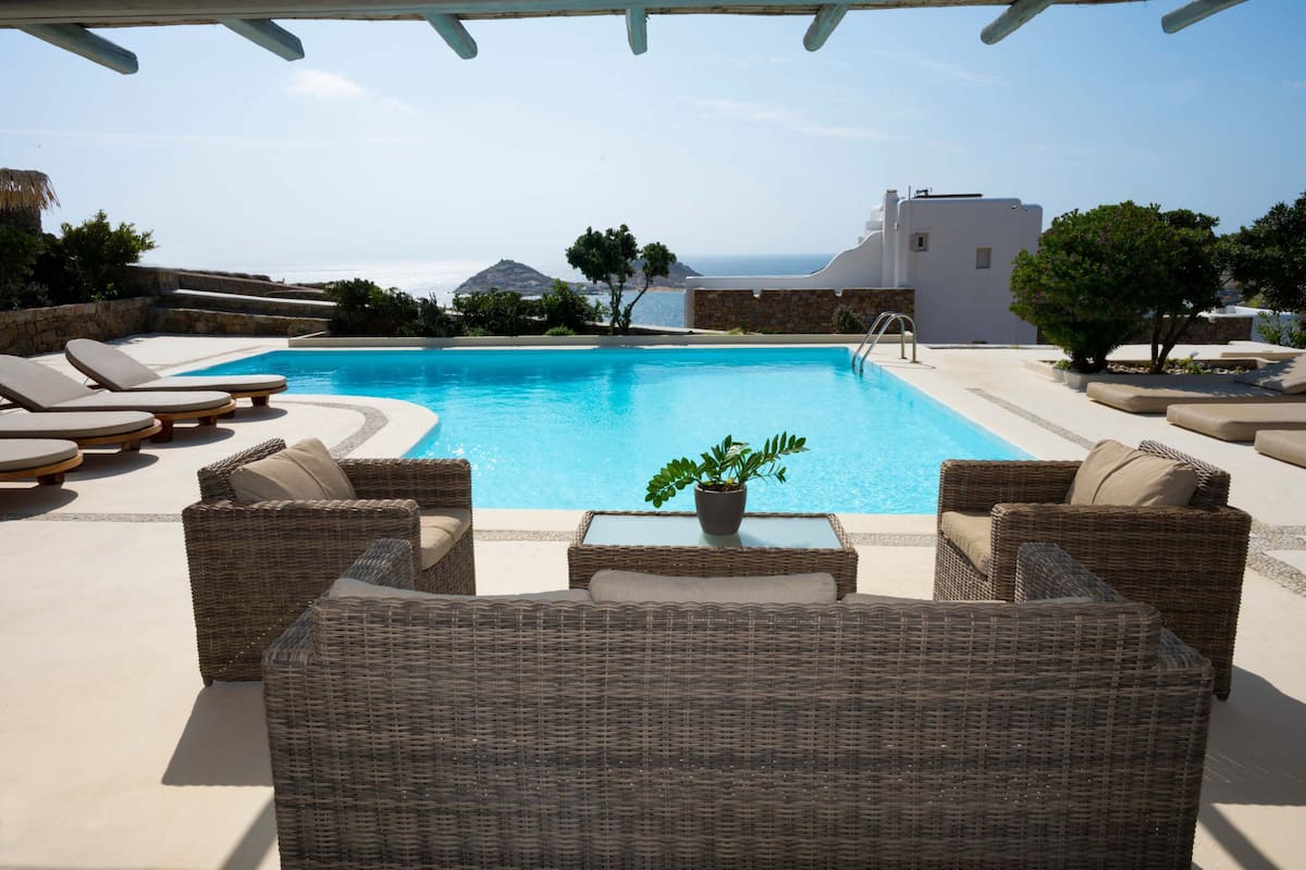 A poolside area with wicker furniture and a potted plant.