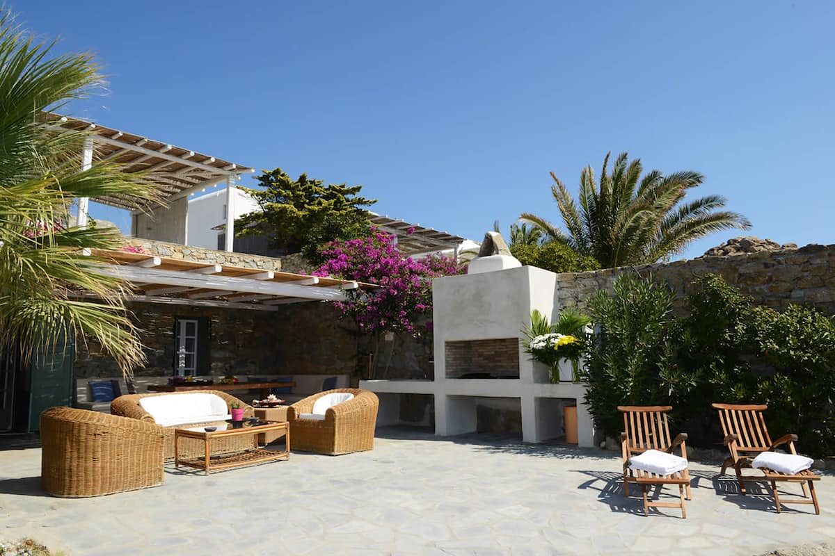 A patio area with wicker furniture, a stone floor, and a pergola.