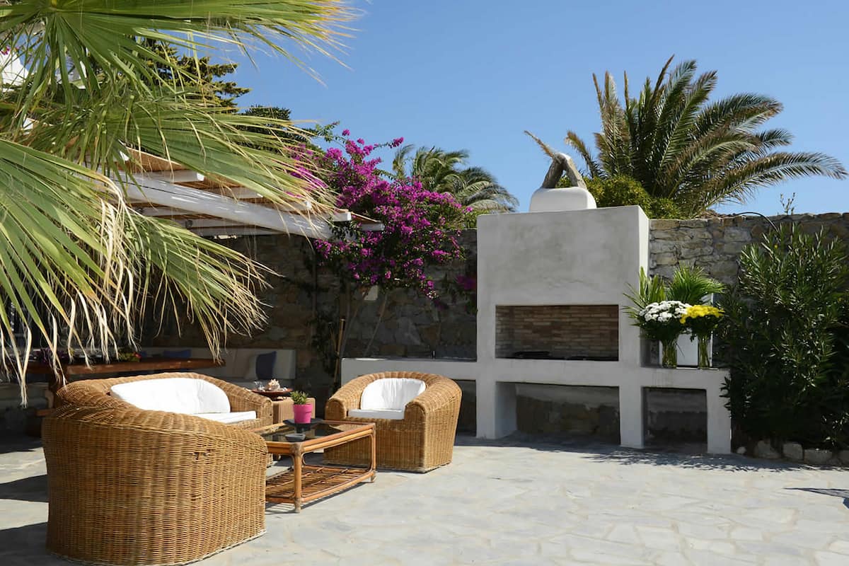 An outdoor patio with wicker furniture, a stone wall, and a built-in fireplace.