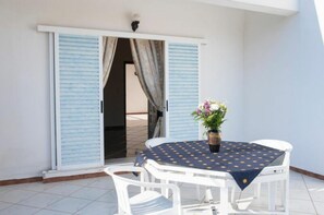 Ein Balkon mit Tisch, Stühlen, einer Topfpflanze und blauen Fensterläden.